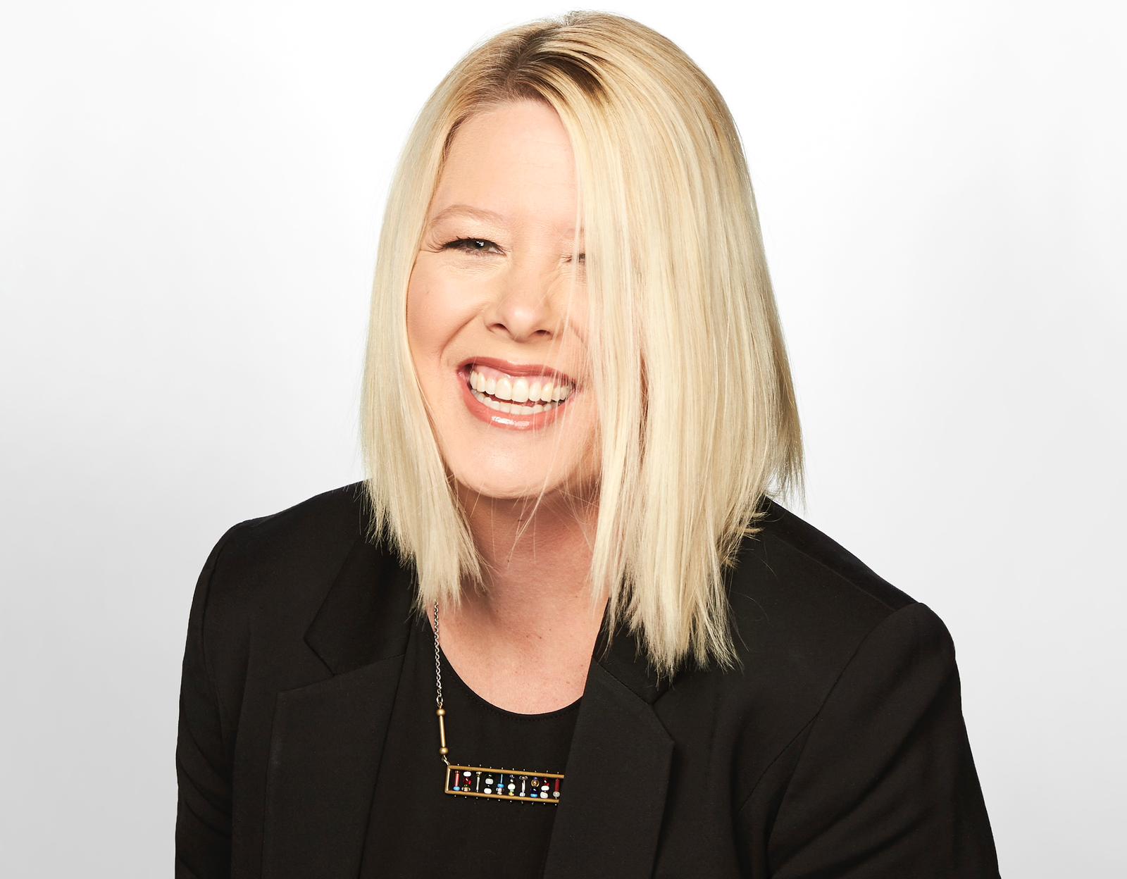 Emma May-Bradley smiling in a black blazer against a white background