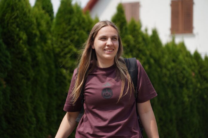 Laura Lücker, Organizational Lead of 1. FC Nürnberg’s women’s team, walking outdoors in casual club attire with a backpack.