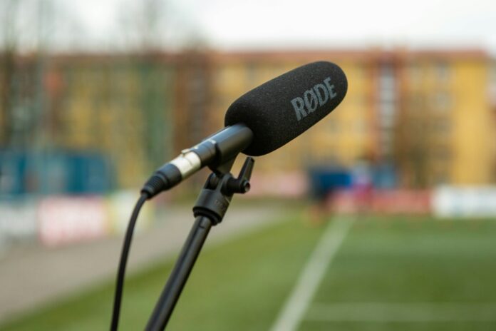 RØDE microphone positioned pitch-side at a football stadium, symbolizing media and communication in the sport.