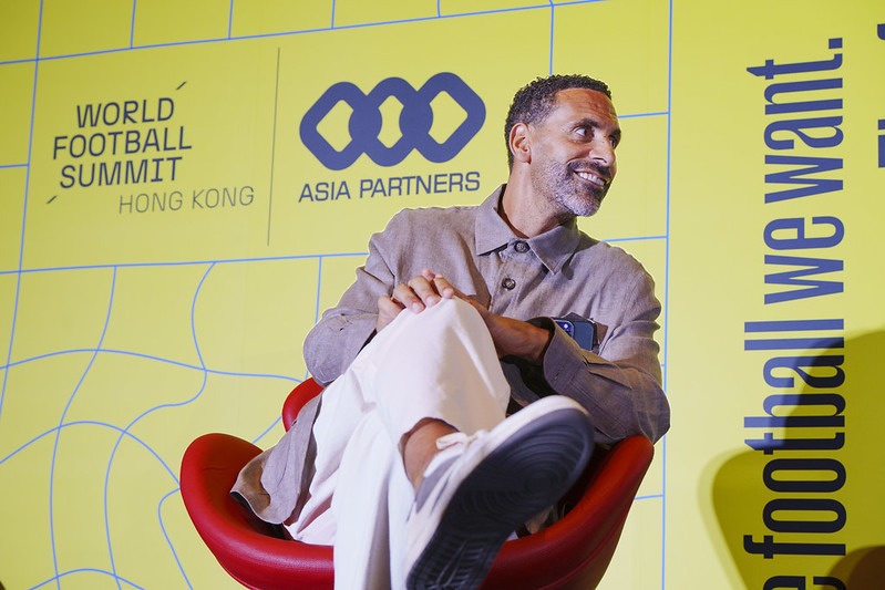 Former professional footballer speaking at the World Football Summit Hong Kong 2025, seated on stage with the Asia Partners logo in the background.