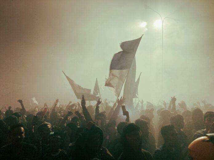 Football fans waving flags and celebrating together, symbolizing the importance of community and trust in the game.