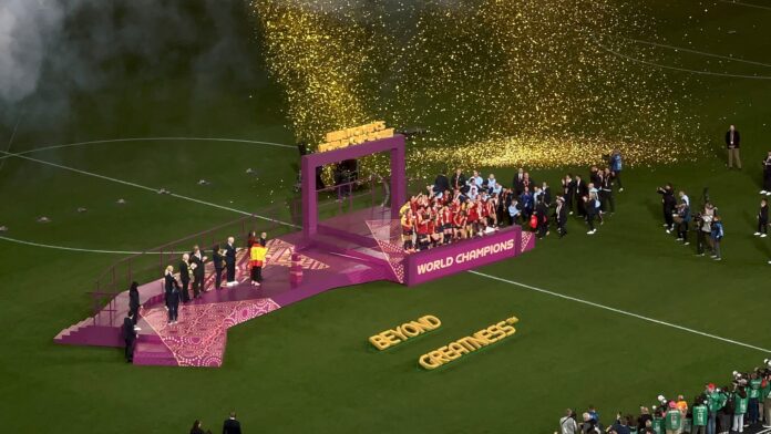 Celebration at the 2023 FIFA Women's World Cup Final as champions lift the trophy with golden confetti at the stadium.