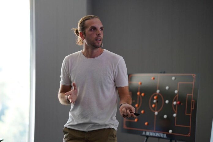 Andrés García presenting tactical insights with a football strategy board during a coaching session.