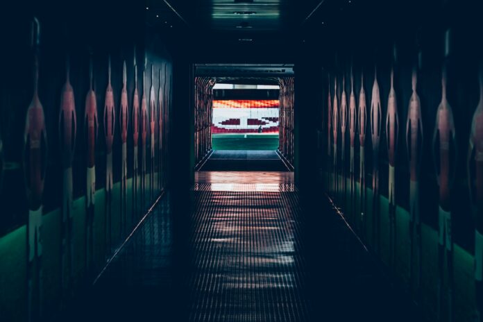 Empty stadium tunnel leading to the pitch, symbolising the pre-game walk that has become a fashion showcase in modern football.