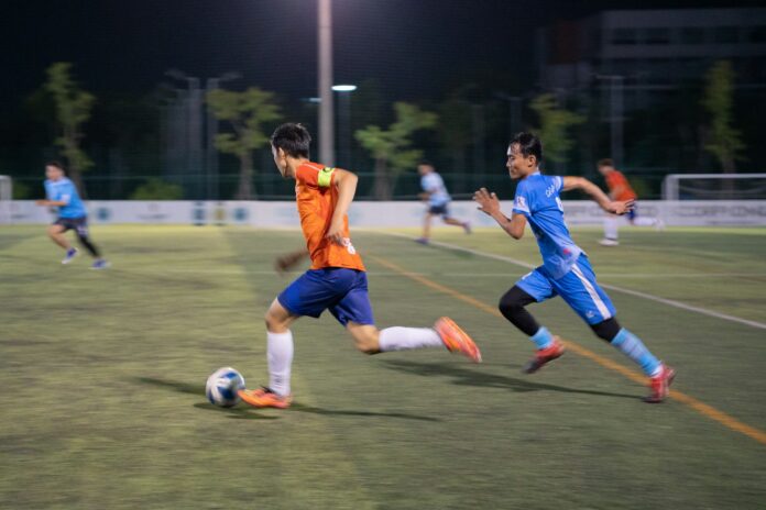 Football players in action during a night match in Phnom Penh, Cambodia.