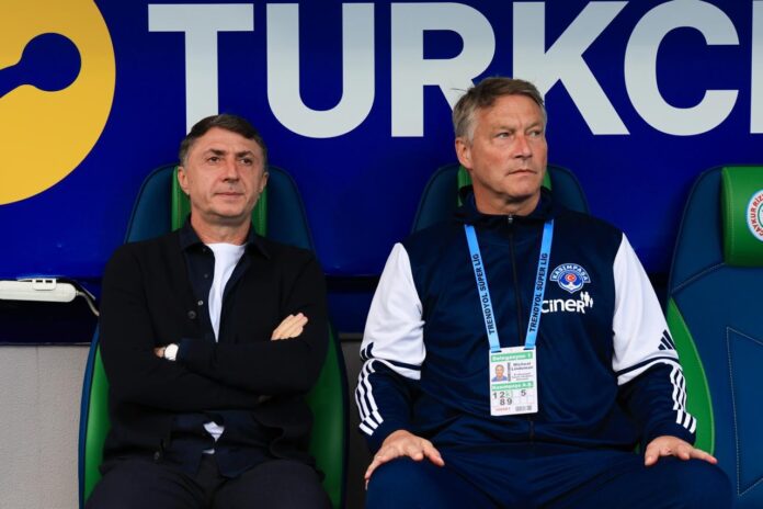 Michael Lindeman and Shota Arveladze seated in the dugout, focused before kickoff.