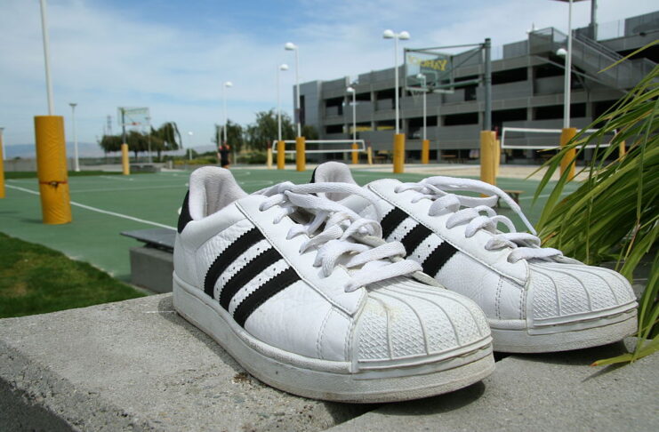 Adidas Superstar sneakers placed outdoors, symbolizing the timeless connection between sport, fashion, and culture.