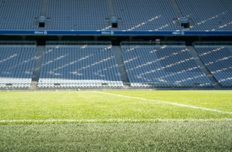 Empty football stadium with clean seating and pitch lines, symbolising the financial and structural side of the football industry.