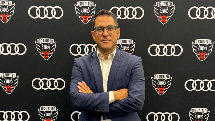 Erkut Sogut Dr. Erkut Sogut, Managing Director of Soccer Operations at D.C. United, stands in front of the club’s logo backdrop.