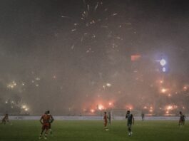 Casablanca Derby: Passion Beyond the Pitch Police officers watch as flares and smoke light up the stands during the Casablanca Derby between Wydad and Raja at Mohammed V Stadium.