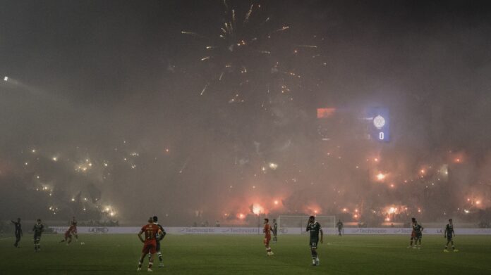 L1000155C Police officers watch as flares and smoke light up the stands during the Casablanca Derby between Wydad and Raja at Mohammed V Stadium.