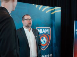 Mario Roitman, President of Miami FC, speaks at a club event in front of the team’s logo backdrop.