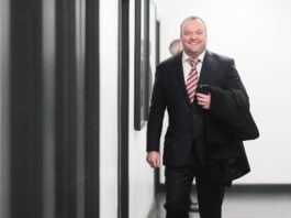 Who is Mark Cartwright? Mark Cartwright walking through a stadium hallway in a suit, reflecting his role as a leading modern sporting director.