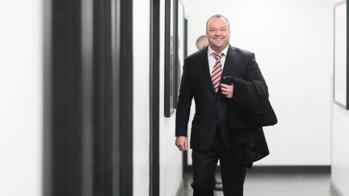 Mark Cartwright walking through a stadium hallway in a suit, reflecting his role as a leading modern sporting director.
