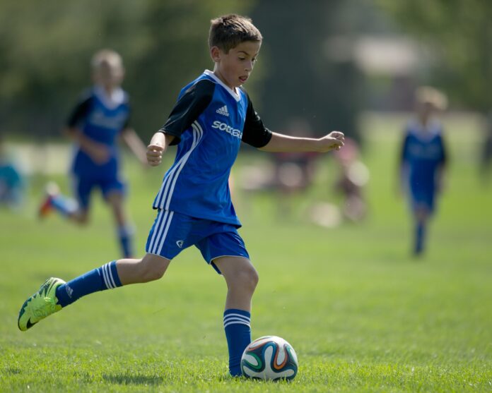 Youth football player controlling the ball during a match, representing issues around international transfers of minor players.