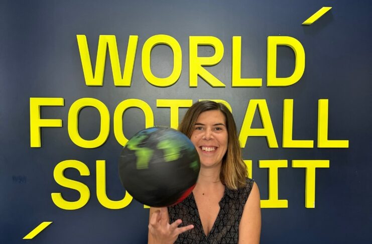 Arantxa Mandiola smiling in front of the World Football Summit backdrop while spinning a globe-themed football.