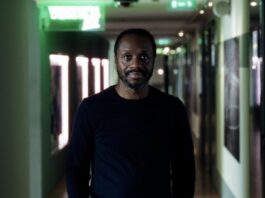 Ben Manga standing in a stadium hallway, reflecting his role as one of European football’s leading scouting and talent directors.