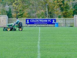 Groundskeeper mowing the pitch at Coldstream FC, highlighting essential behind-the-scenes work in football.