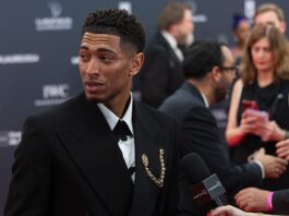 Jude Bellingham wearing a black suit at a fashion event, reflecting the intersection of football and high fashion.