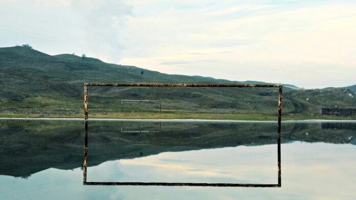 Calm reflective water surface mirroring distant hills, symbolising fluidity and adaptability in the modern game.