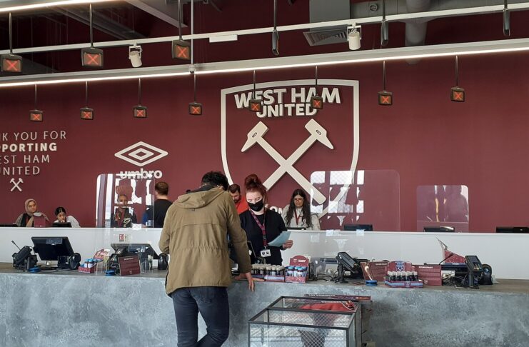 West Ham stadium store with supporters browsing merchandise, highlighting the club’s working-class roots and industrial identity.