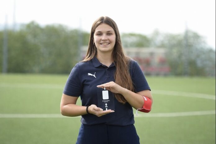 Catarina Martins holding a recognition award on a football pitch, reflecting her role in women’s football operations and development.