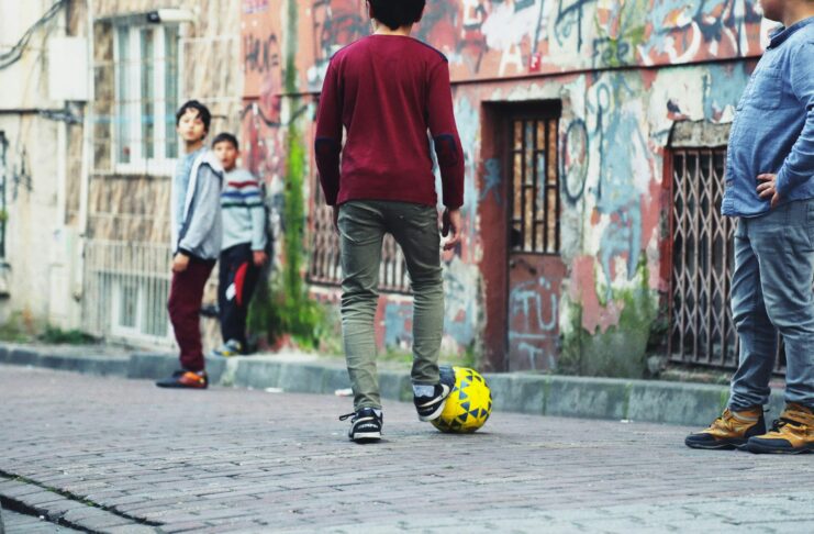 Children playing street football in an urban setting, reflecting grassroots engagement and community impact in the football ecosystem.