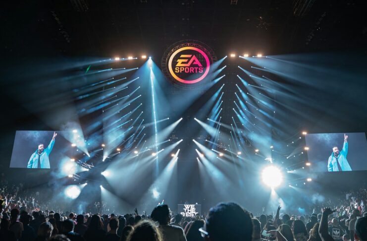 EA Sports logo displayed above a live esports arena stage with bright lights and a cheering crowd.