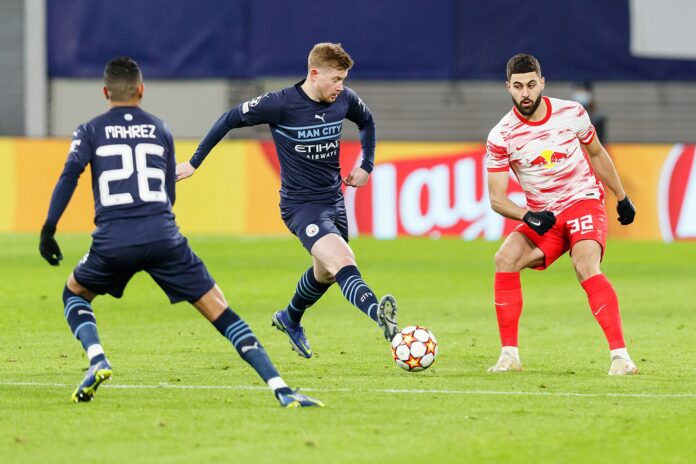 Kevin De Bruyne plays a forward pass for Manchester City under pressure in a Champions League match