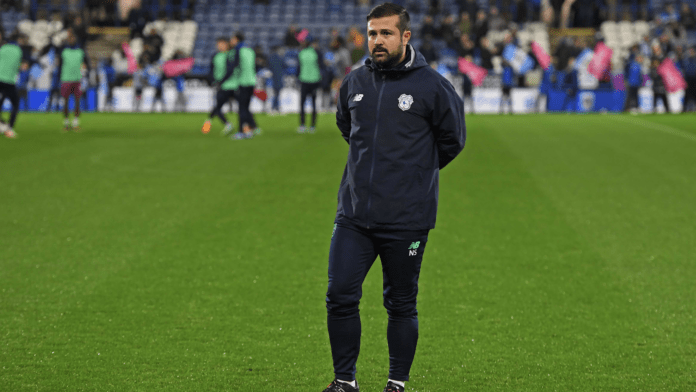 Nadir Sönmez, UEFA A Licensed football coach, standing on the pitch during a matchday warm-up at a professional stadium.