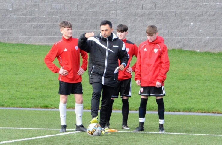 Norberto Rodrigues Da Silva gives tactical instructions to youth players during a training session on the pitch.