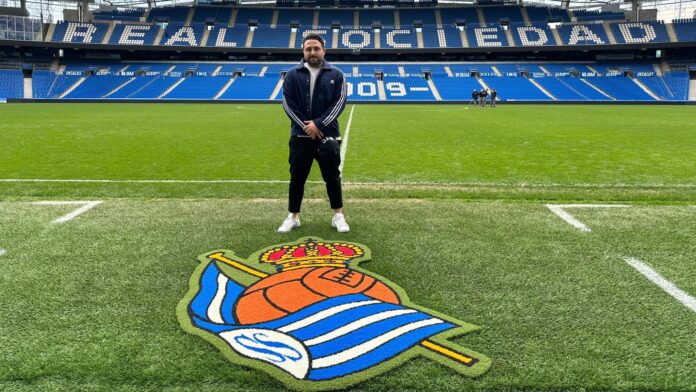 Sacha Esteves standing on the pitch at Real Sociedad’s stadium, reflecting his scouting work and connection to elite youth development.